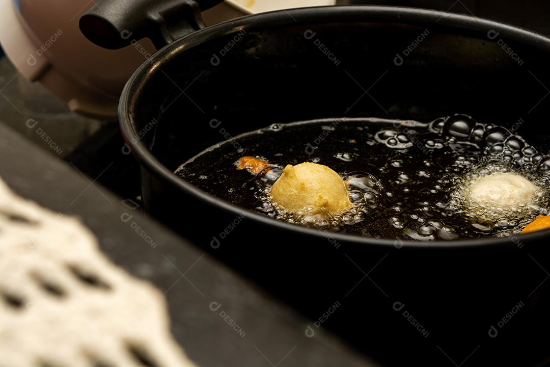 pegando a massa frita conhecida como bolinho de chuva com uma escumadeira. lanche típico e tradicional brasileiro.