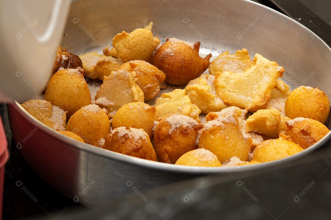 colocando açúcar e canela em uma massa frita conhecida como bolinho de chuva. uma receita típica e tradicional brasileira
