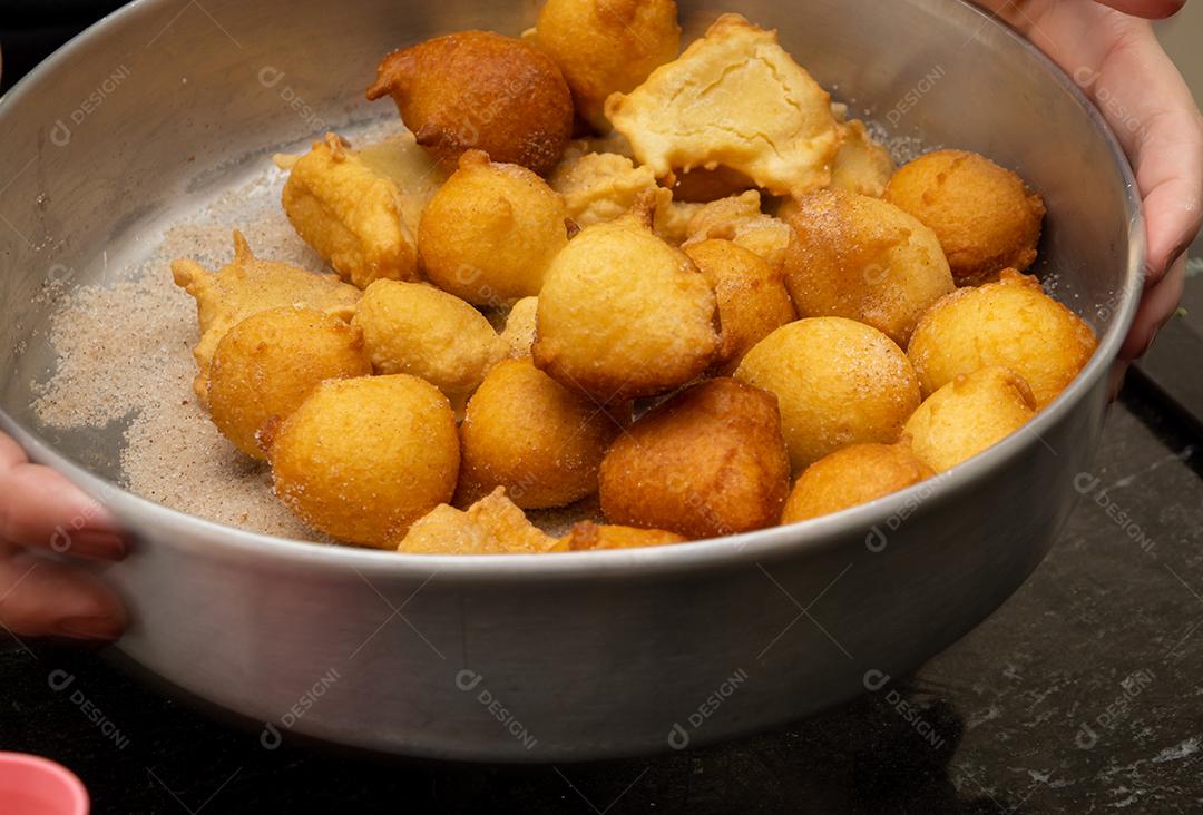 colocando açúcar e canela em uma massa frita conhecida como bolinho de chuva. uma receita típica e tradicional brasileira
