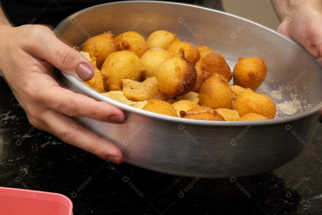 colocando açúcar e canela em uma massa frita conhecida como bolinho de chuva. uma receita típica e tradicional brasileira