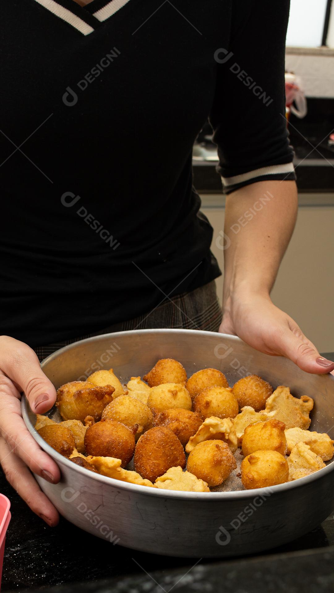 woman putting sugar and cinnamon into a deep-fried dough known as dumplings. a typical and traditional Brazilian recipe