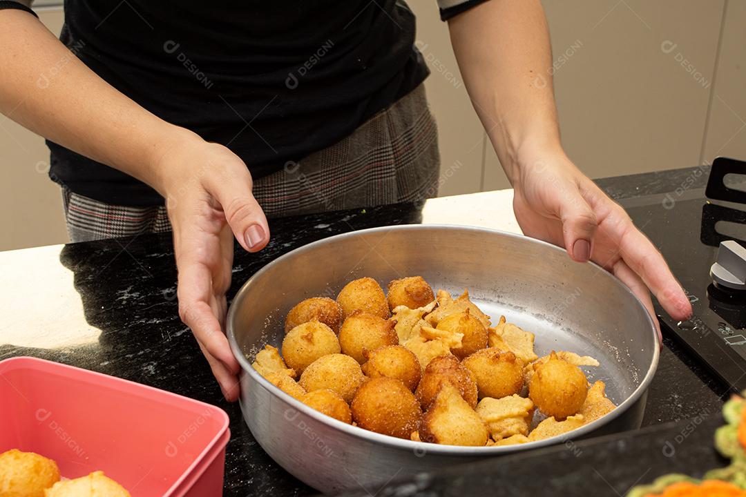 mulher colocando açúcar e canela em uma massa frita conhecida como bolinho de chuva. uma receita típica e tradicional brasileira