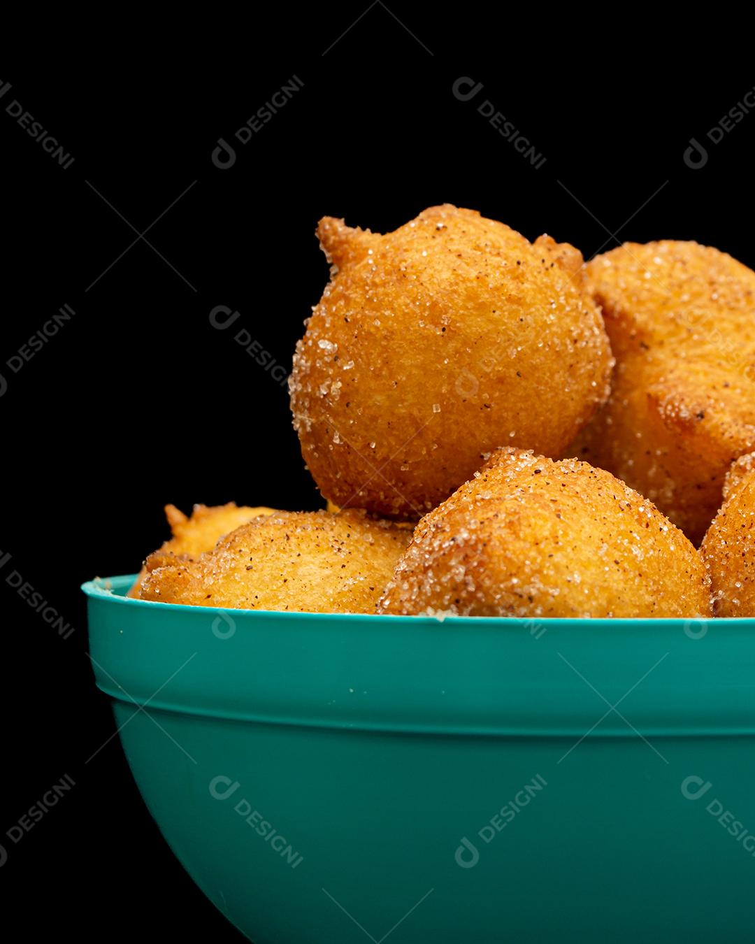 bolinho de chuva, receita tradicional brasileira, feita de massa frita com açúcar e canela, em pote azul e fundo preto. tiro vertical