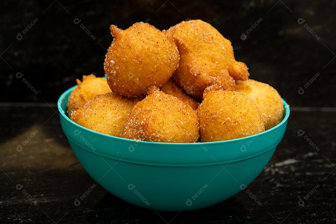 bolinho de chuva, receita tradicional brasileira, feita de massa frita com açúcar e canela, em pote azul e fundo preto