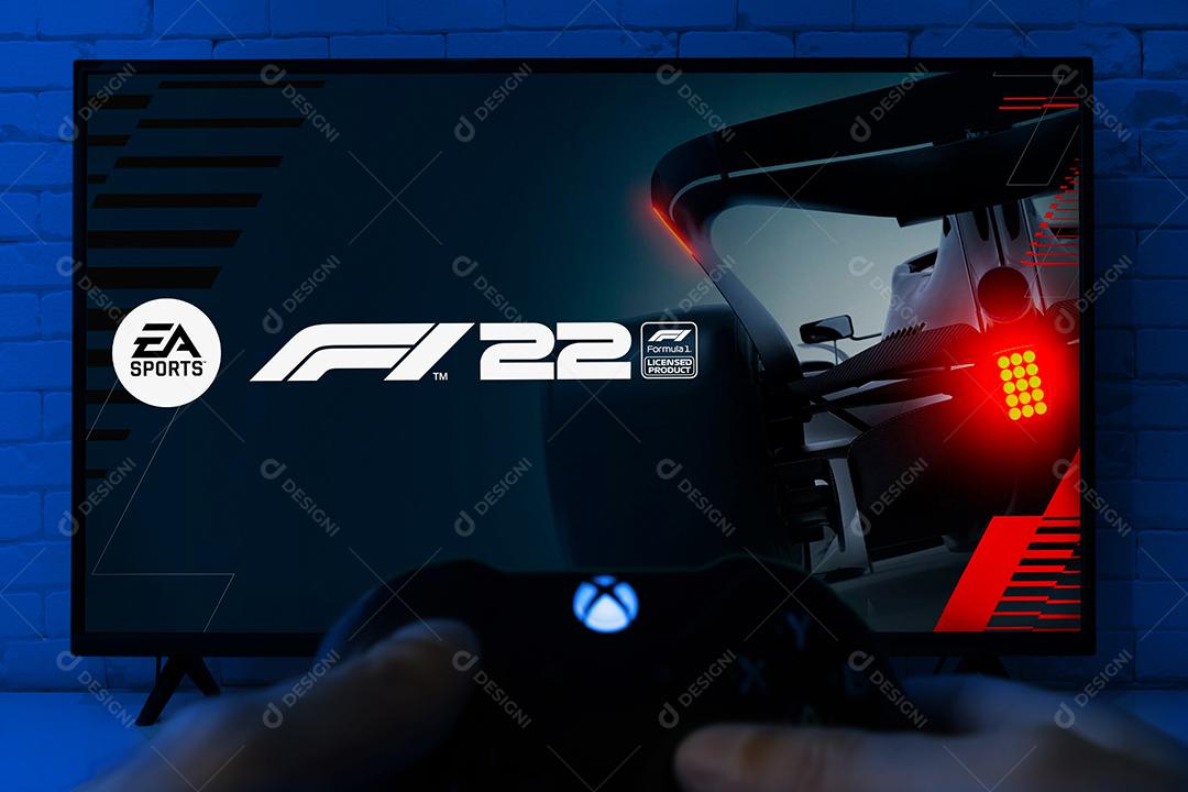 Homem segurando o controle do Xbox Series e jogando F1 22 na TV, foco seletivo