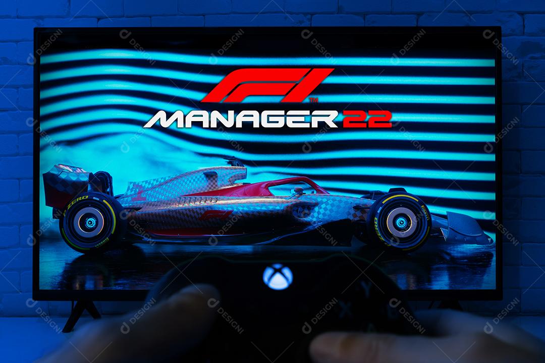 Homem segurando o controle do Xbox Series e jogando F1 Manager 22 na TV
