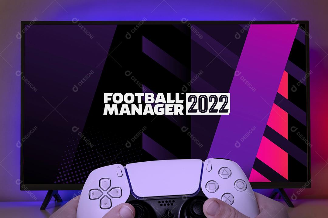 Garoto segurando o controle do Playstation 5 e jogando Football Manager 2022 na TV