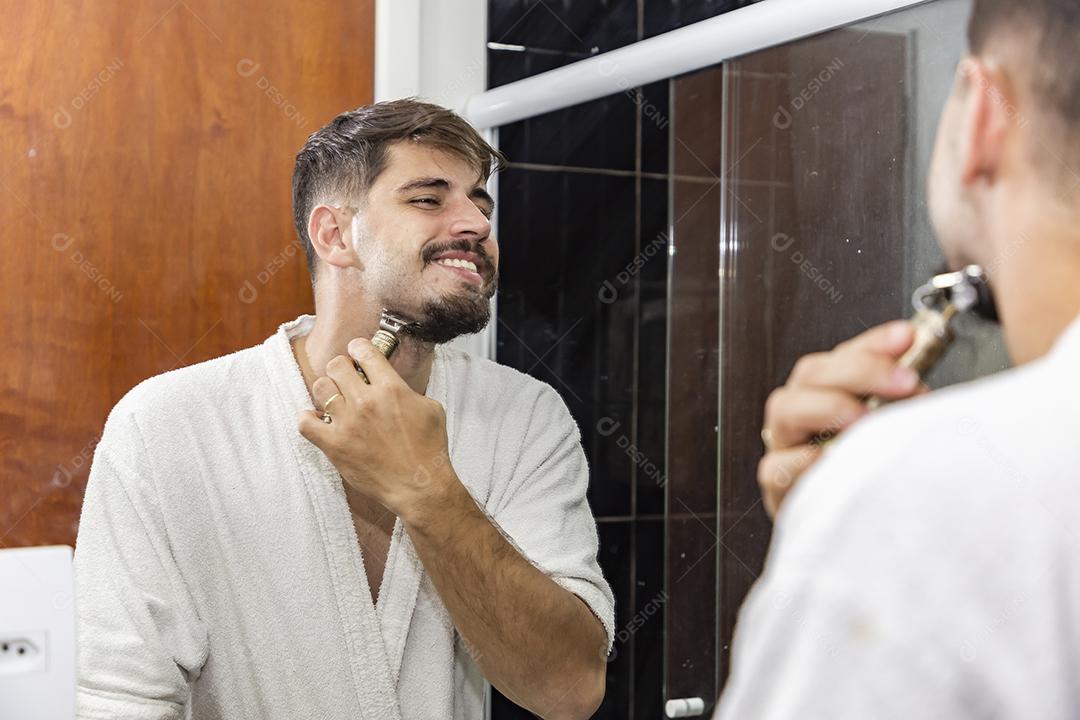 Rapaz bonito jovem fazendo a barba no banheiro.