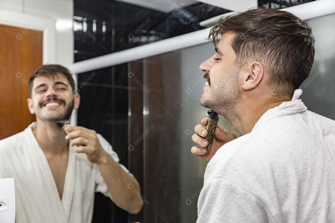Rapaz bonito jovem fazendo a barba no banheiro.