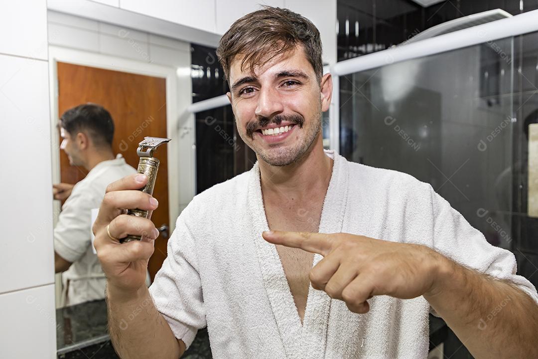 Rapaz bonito barbear no banheiro segurando uma navalha