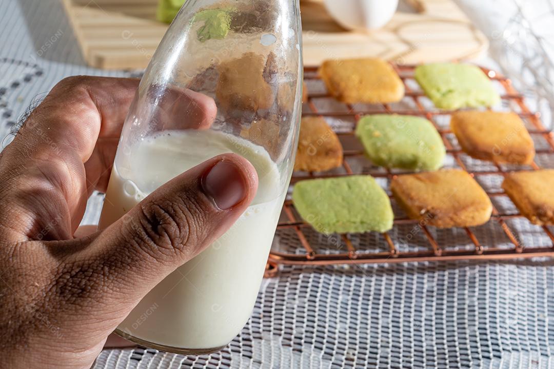 Mão masculina segurando fresco com leite em mesa de madeira com pano branco