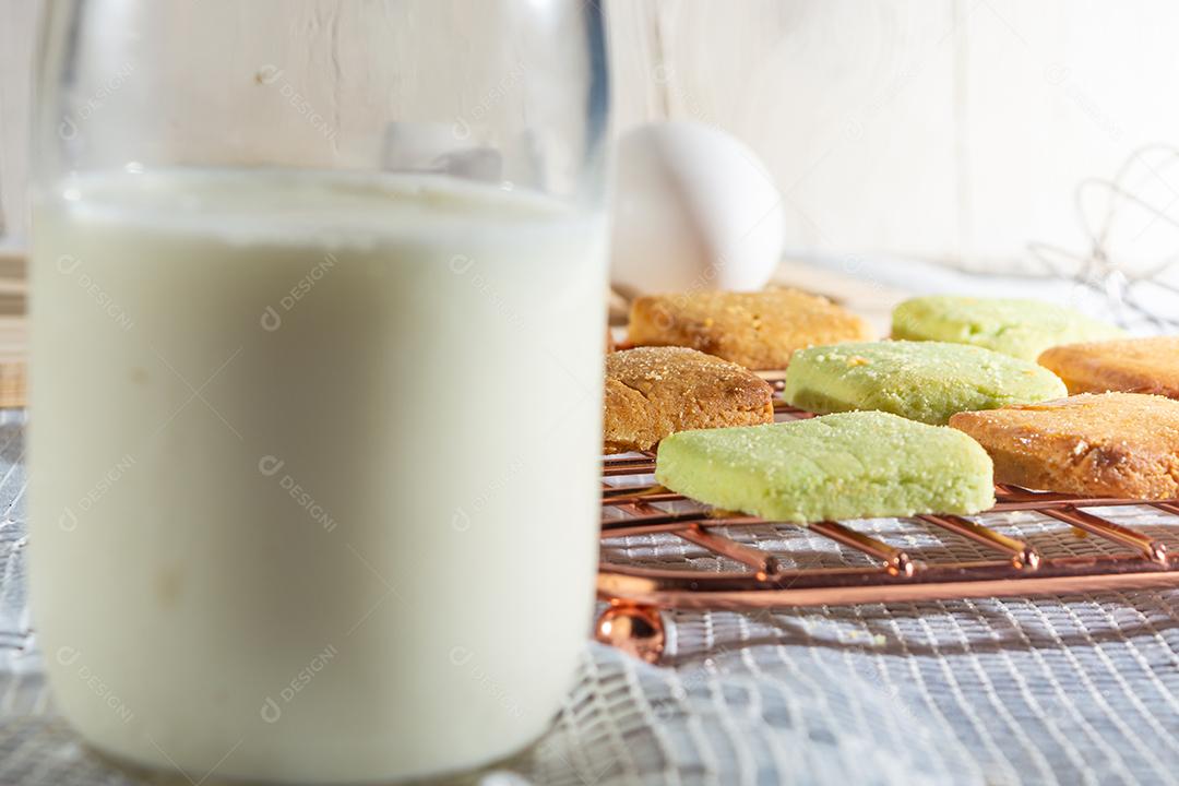 Bolinhos de polvilho com doce por cima sobre mesa com grade copo leite