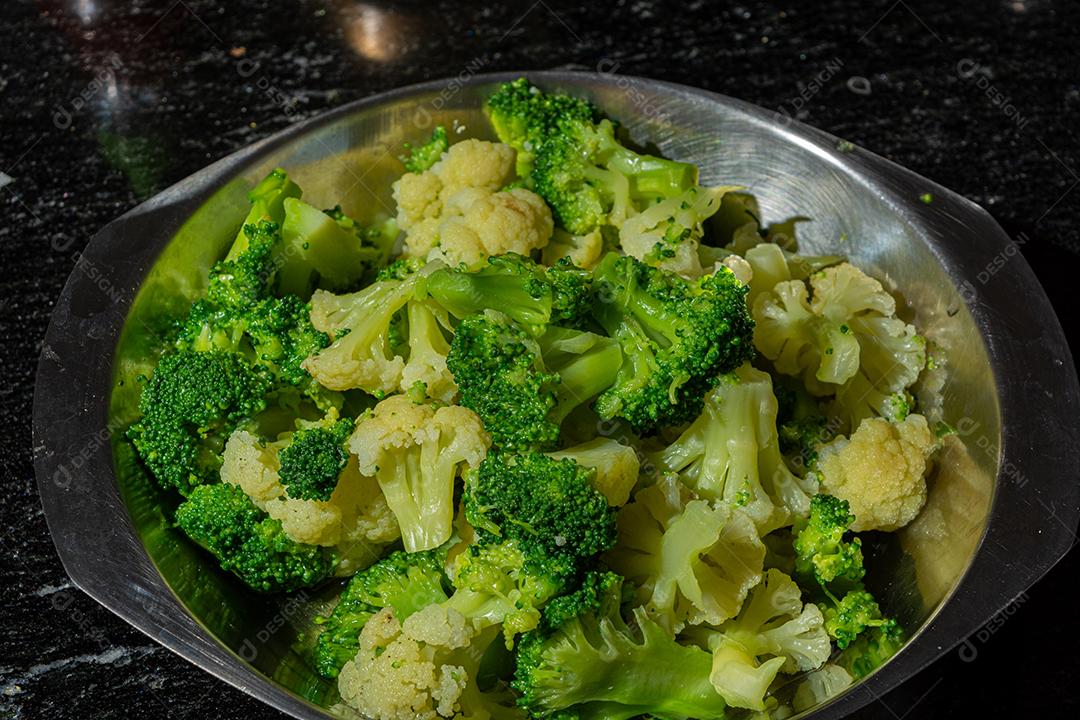 Brócolis cozidos com garfo sobre panela. Verdura