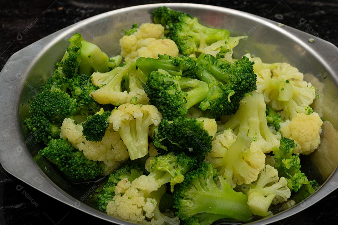 Brócolis cozidos com garfo sobre panela. Verdura