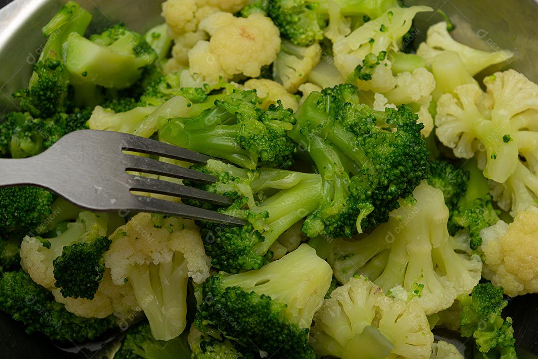 Brócolis cozidos com garfo sobre panela. Verdura