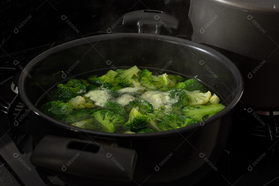 Brócolis com água em panela preto sobre fogão. Verdura