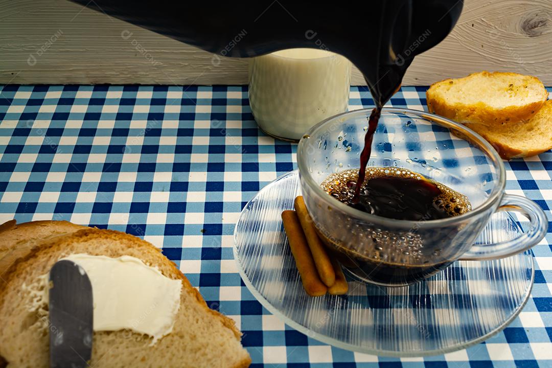 Pão com manteiga, leite, café em xícara, café da manhã, lanche sobre pano xadrez azul  mesa madeira