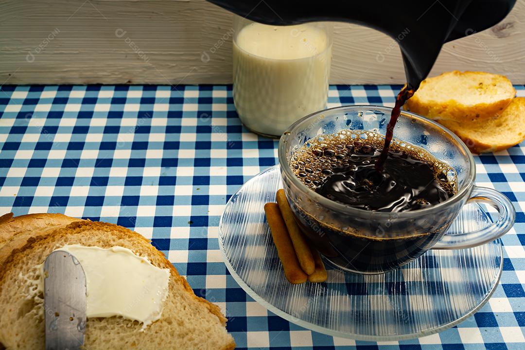 Pão com manteiga, leite, café em xícara, café da manhã, lanche sobre pano xadrez azul  mesa madeira