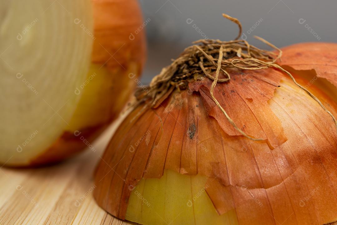 Meia cebola sobre tabua e mesa de madeira, tempero.