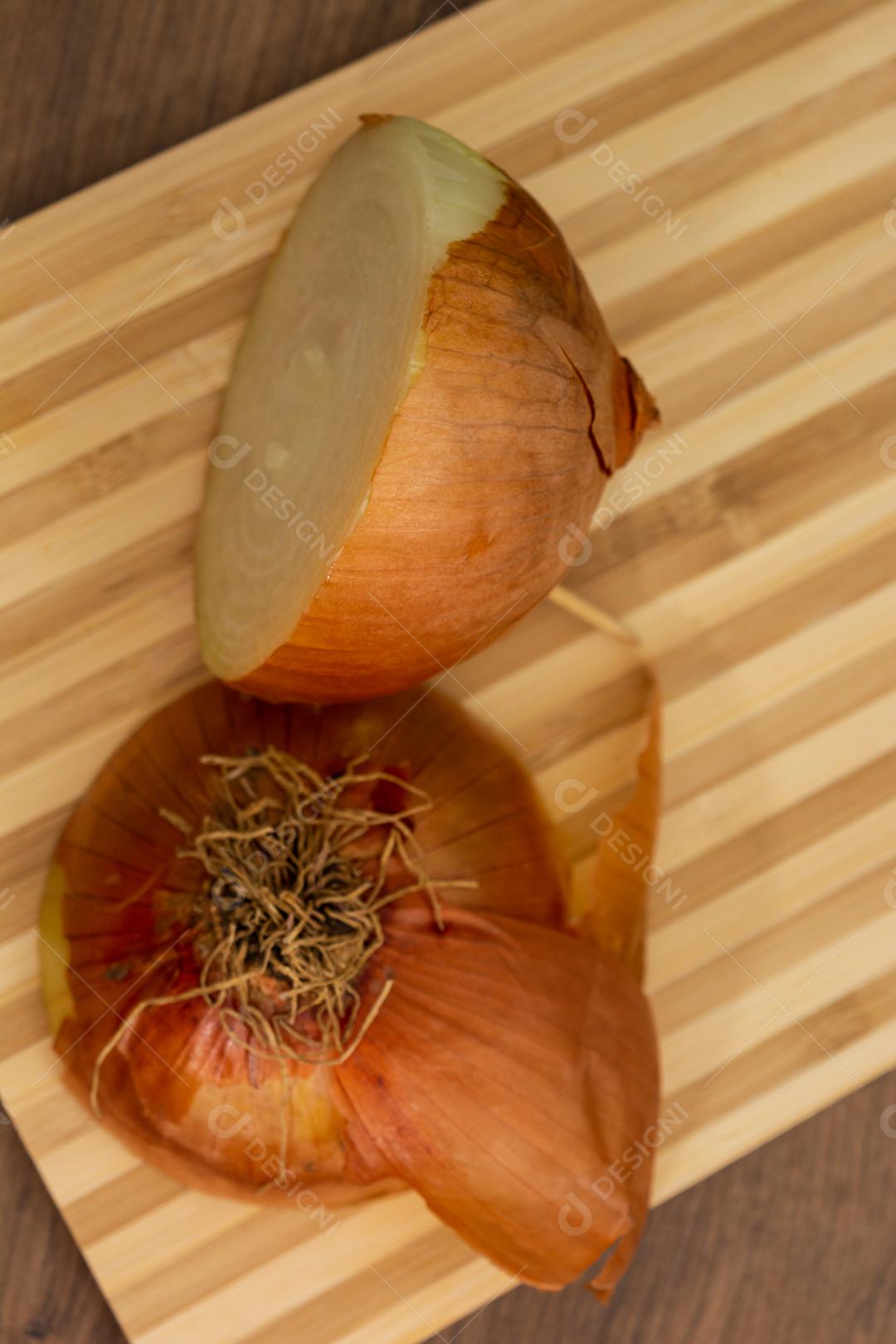 Meia cebola sobre tabua e mesa de madeira, tempero.