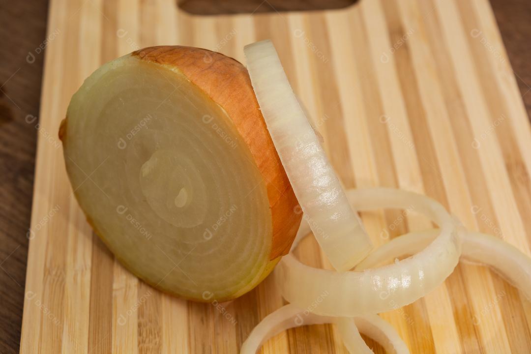 Meia cebola sobre tabua e mesa de madeira, tempero.