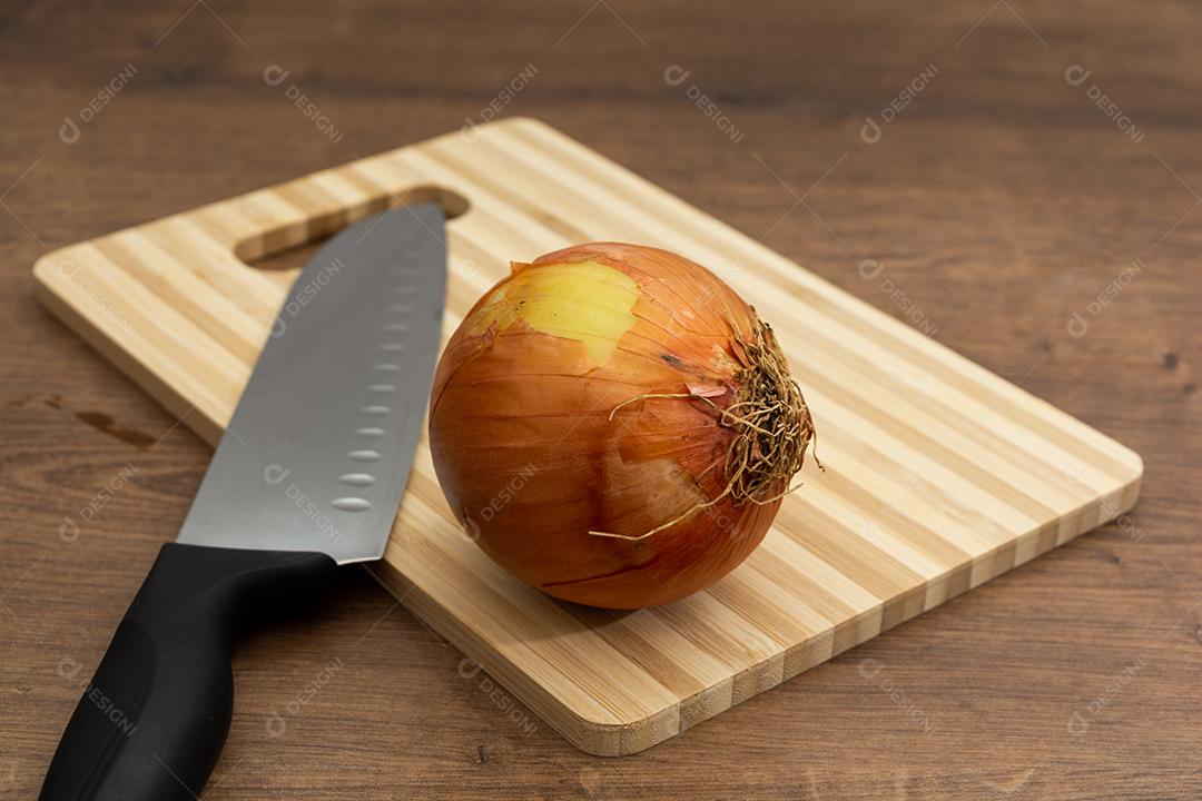 Cebola sobre tabua e mesa de madeira, tempero.