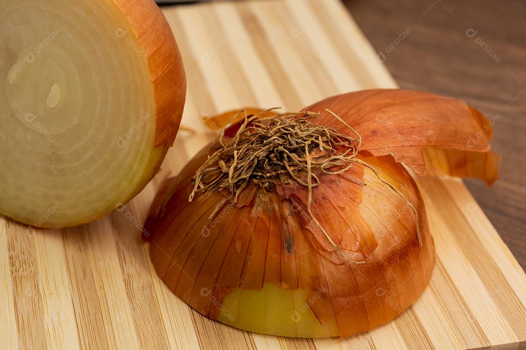 Meia cebola sobre tabua e mesa de madeira, tempero.