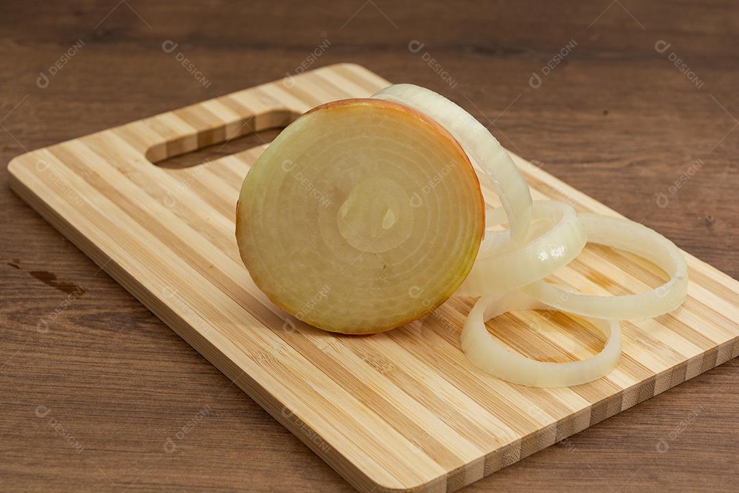 Meia cebola sobre tabua e mesa de madeira, tempero.