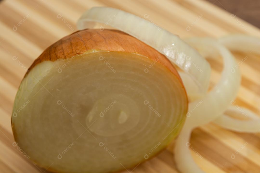 Meia cebola sobre tabua e mesa de madeira, tempero.