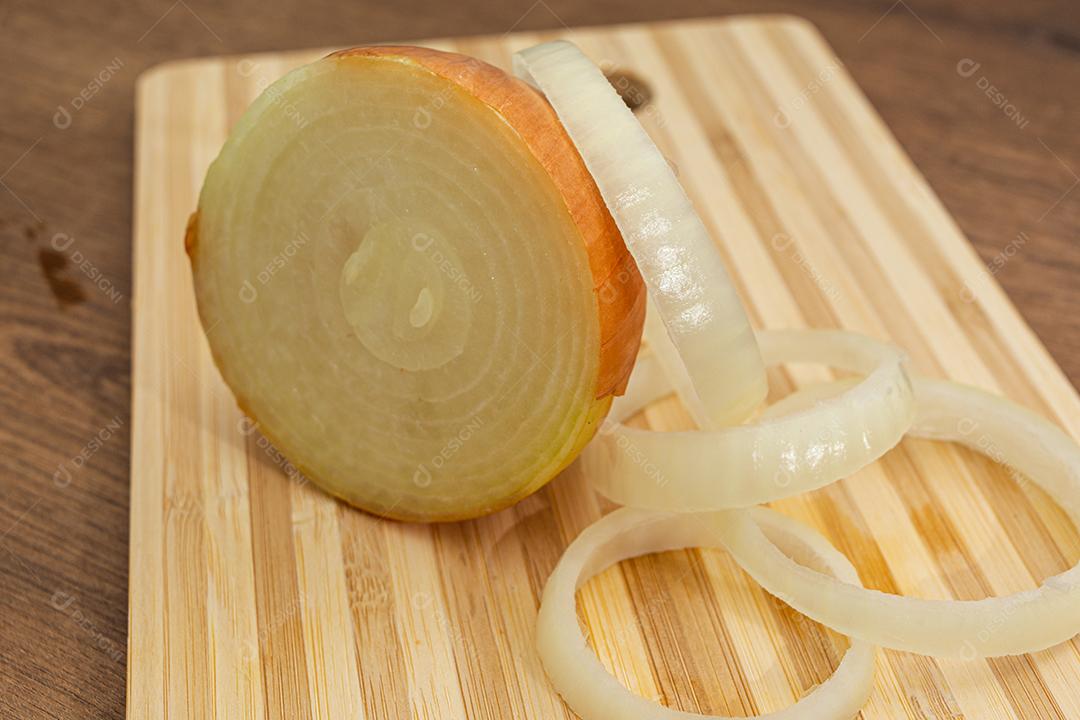 Meia cebola sobre tabua e mesa de madeira, tempero.