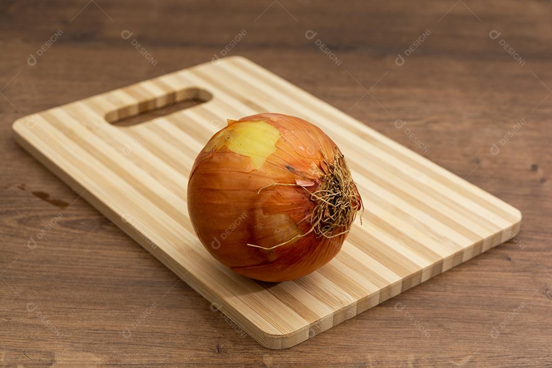 Cebola sobre tabua e mesa de madeira, tempero.