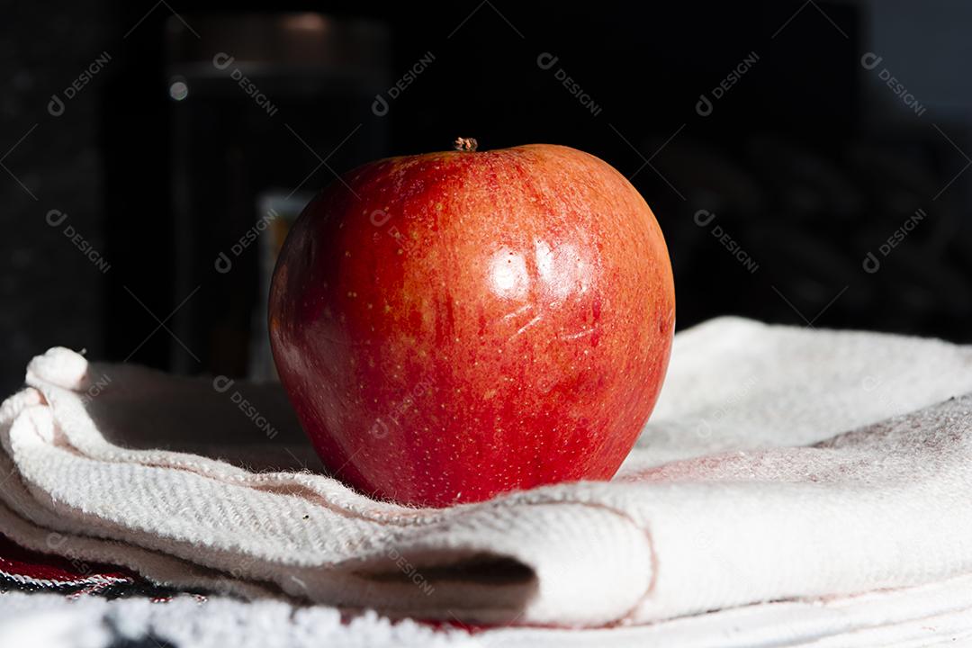 Maçã em pano branco sobre fundo preto.
