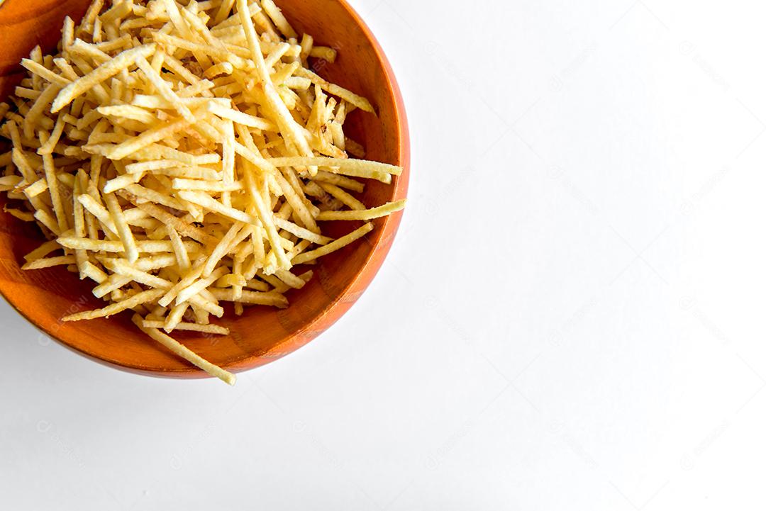 batatas fritas de palha em uma tigela sobre fundo branco.