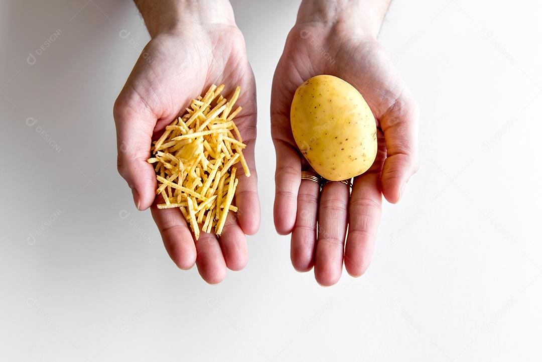 Mãos segurando batata e batata palha.