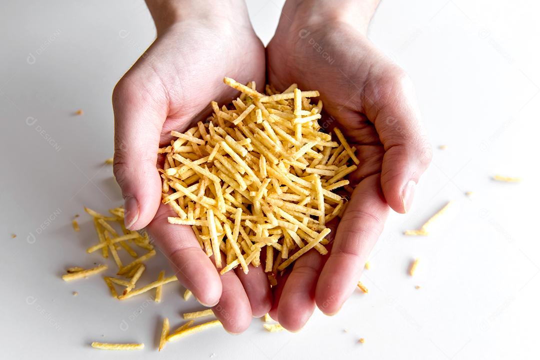 Mãos segurando batatas fritas de palha