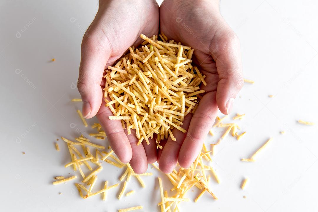 Mãos segurando batatas fritas de palha