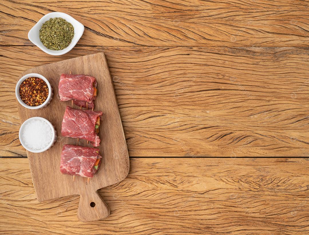 Enrolado de carne ou rocambole, legumes e bacon recheado de carne sobre mesa de madeira com temperos e espaço de cópia.