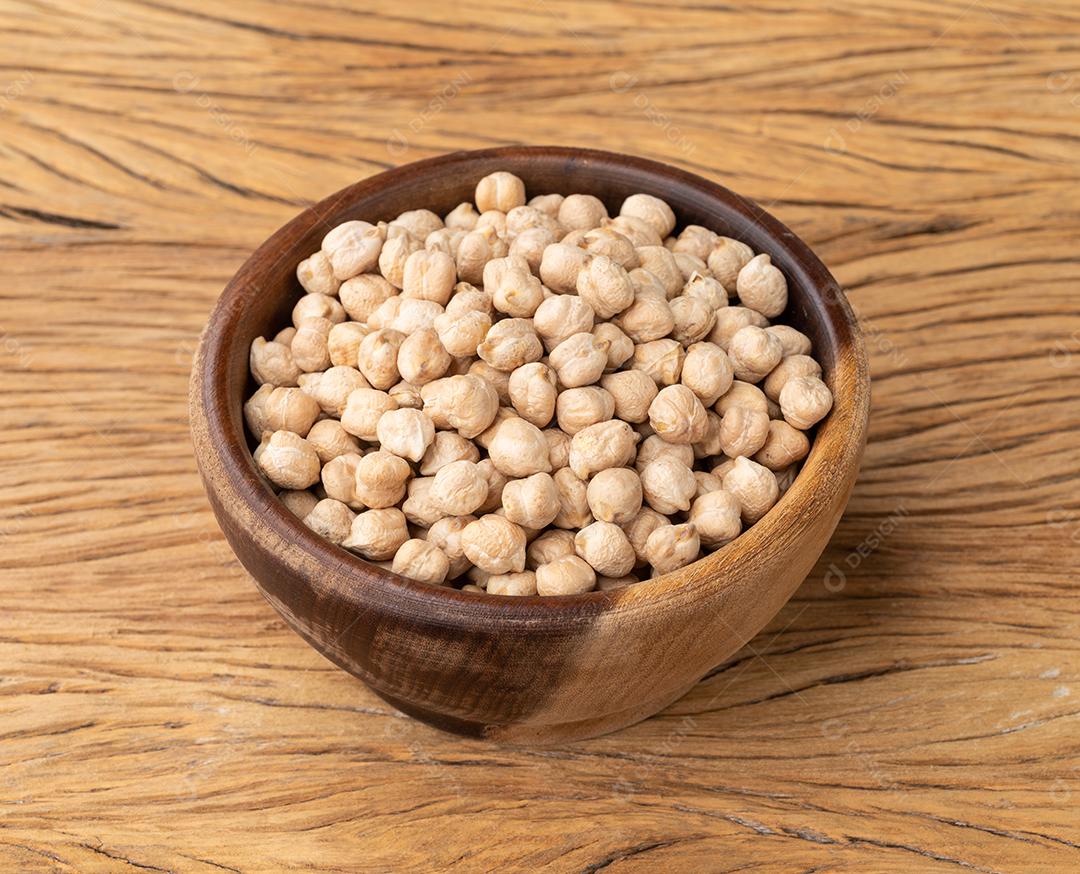 Grão de bico cru em uma tigela sobre a mesa de madeira.