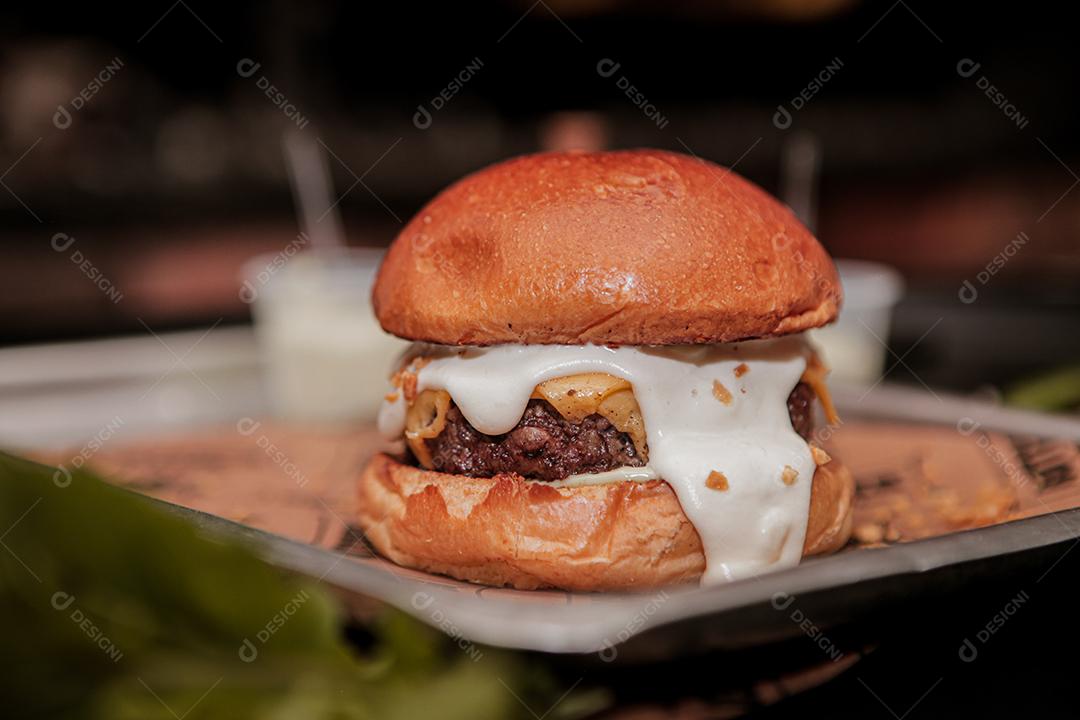 Hambúrguer ,carne grelhada, cheddar, molho branco, queijo.  Foco seletivo