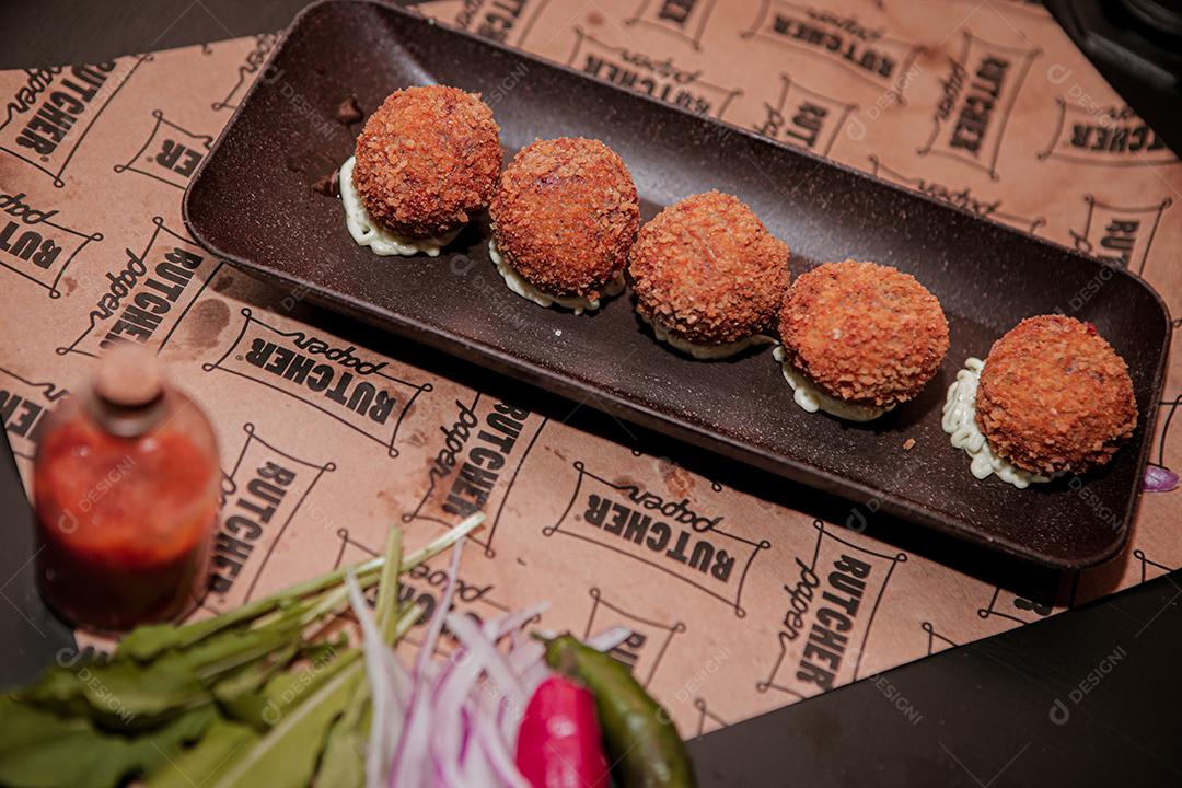 Meat snacks with white sauce on a black background.