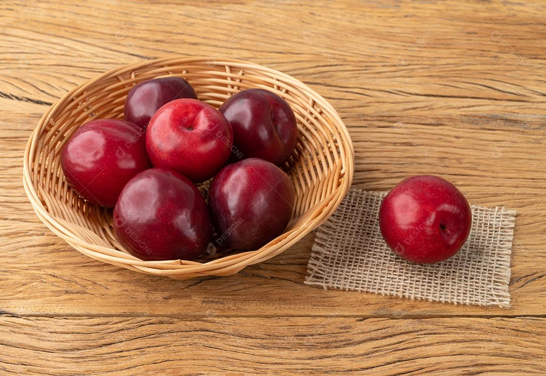 Ameixas em uma cesta sobre a mesa de madeira.