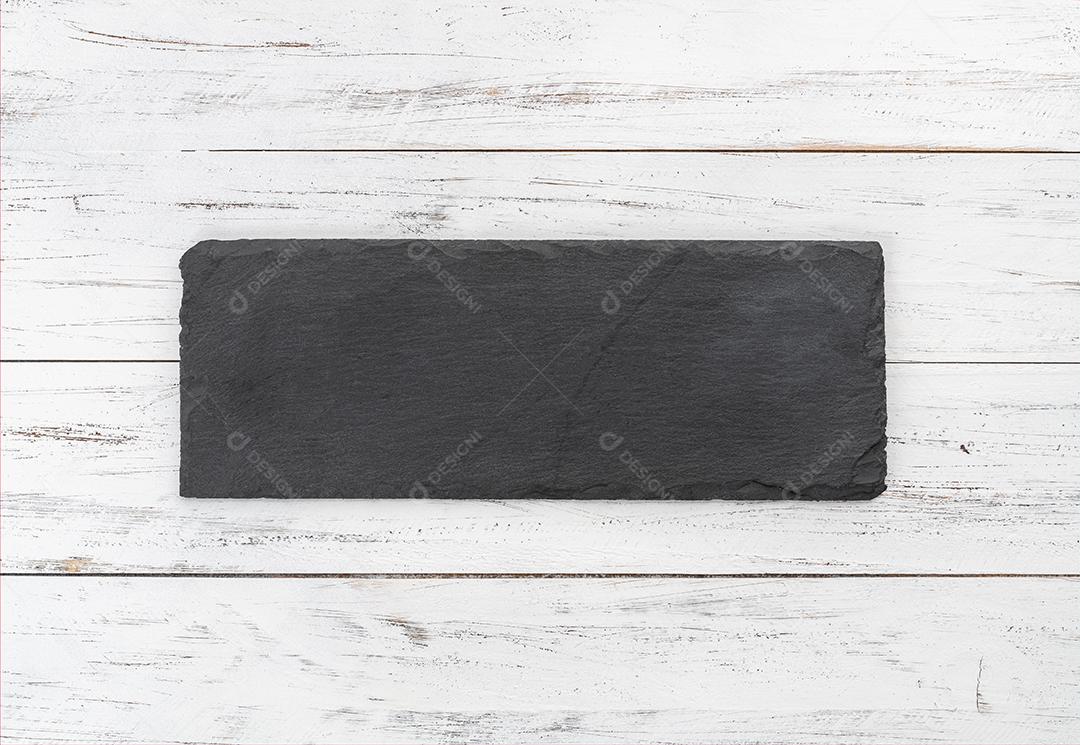 Tábua de pedra vazia sobre a mesa de madeira.
