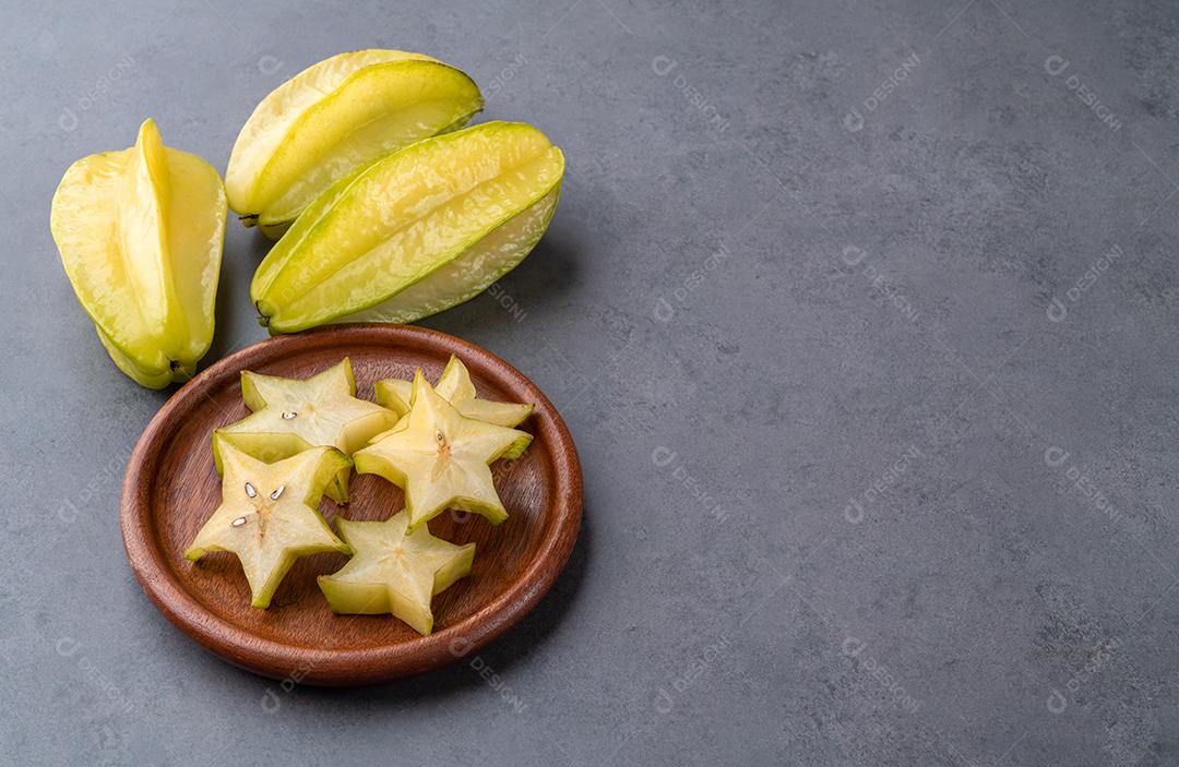Carambolas com fatias em um prato sobre fundo de pedra