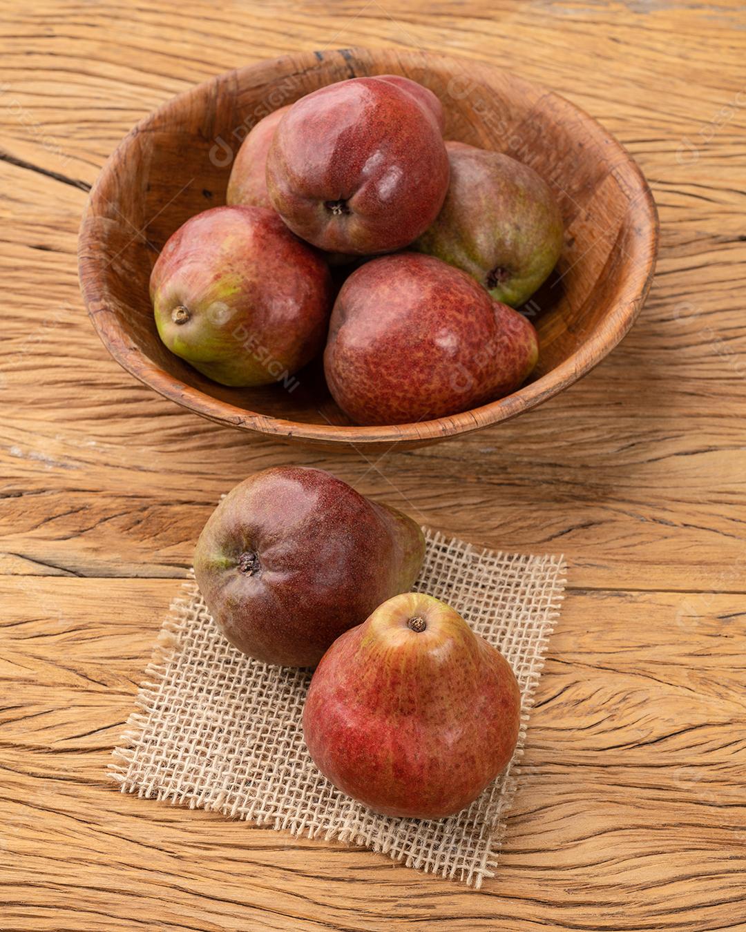 Peras vermelhas em uma tigela sobre a mesa de madeira.