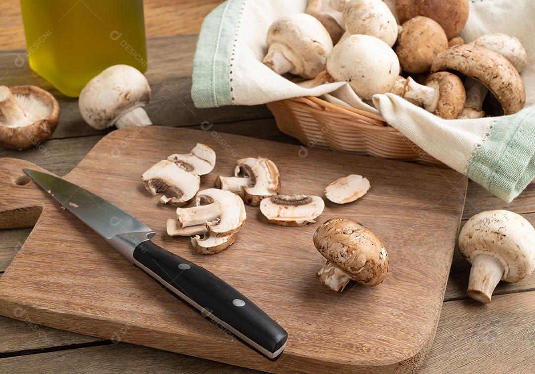 Cogumelos shimeji, portobello e paris em uma cesta sobre a mesa de madeira.