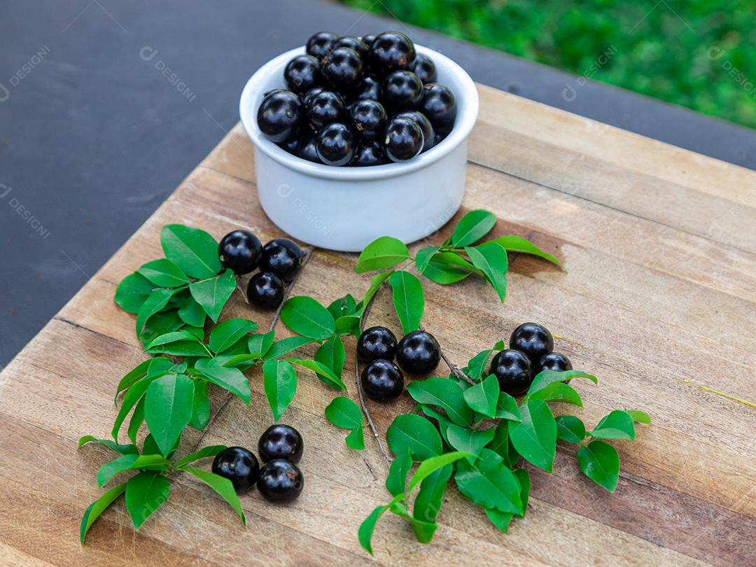 Jabuticaba sobre tigela branca mesa madeira folha verde