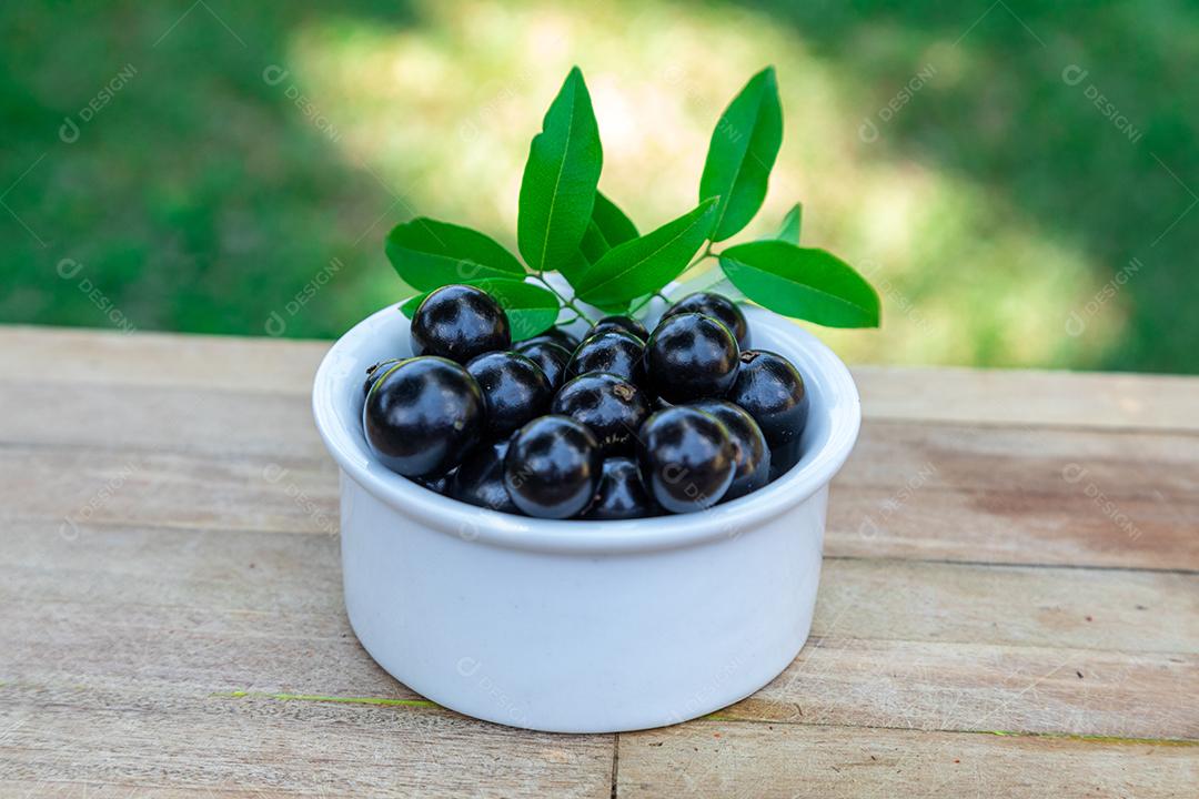 Jabuticaba sobre tigela mesa madeira folha verde