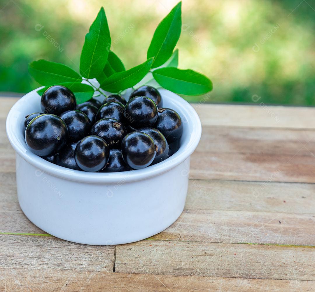 Jabuticaba sobre tigela mesa madeira folha verde