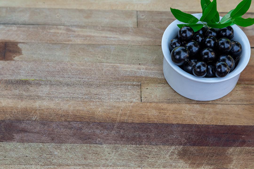 Jabuticabas sobre uma tigela branca mesa madeira