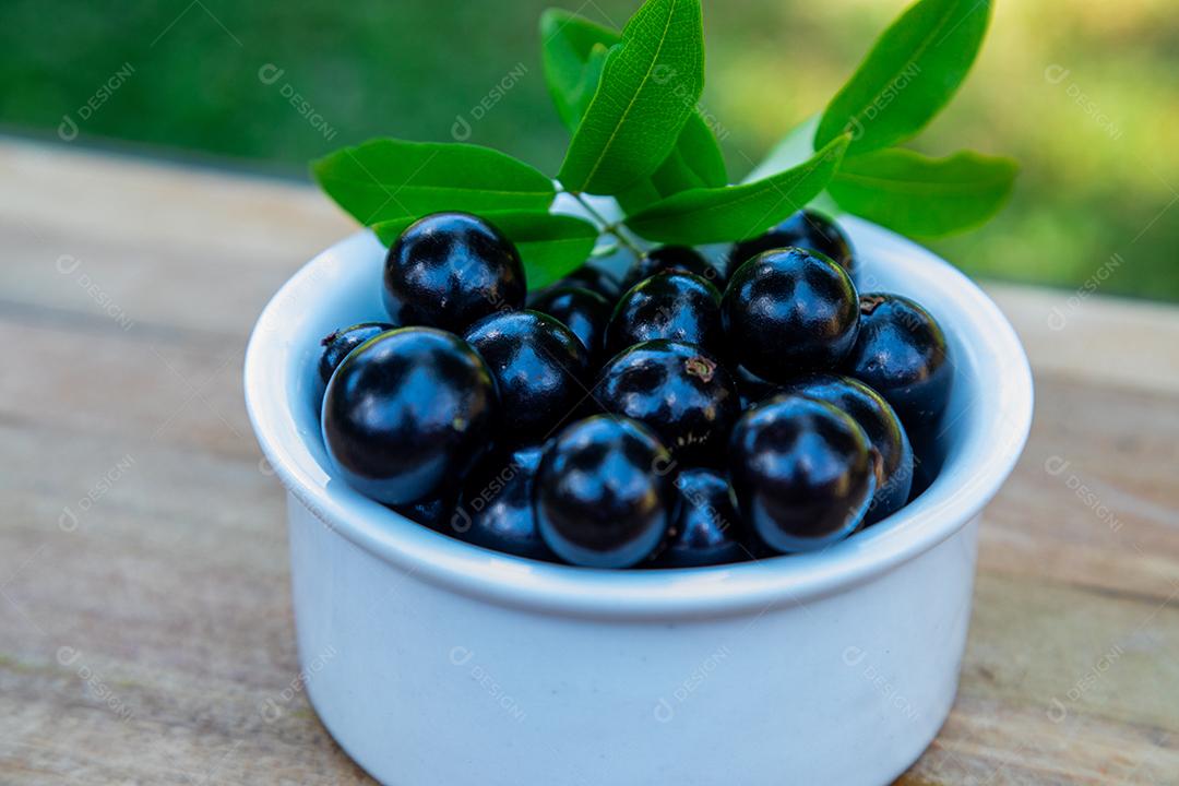 Jabuticaba sobre tigela mesa madeira folha verde